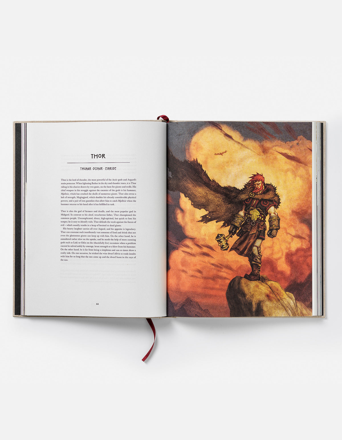 Open Norse Gods book at the Thor chapter, showing red-haired Thor holding a hammer on a rocky ledge beneath an orange sky.